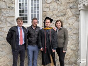 From left: Noel, Brian ‘16, Cameron ’21, and Andrea O’Neill stand outside. Cameron is wearing a black commencement robe and hat.