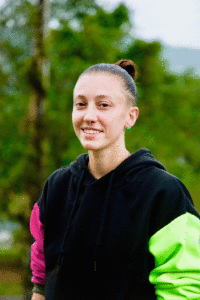 Danielle Bero is pictured in a black, pink, and green shirt. Her hair is in a pony tail.