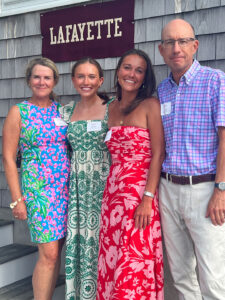 (from left) Betsy Hughes Phillips ’85, Caroline '21, Leslie '23, and Charles Phillips stand outside arm. They are smiling at the camera.