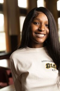 Jada is wearing a white T-shirt and is smiling at the camera.